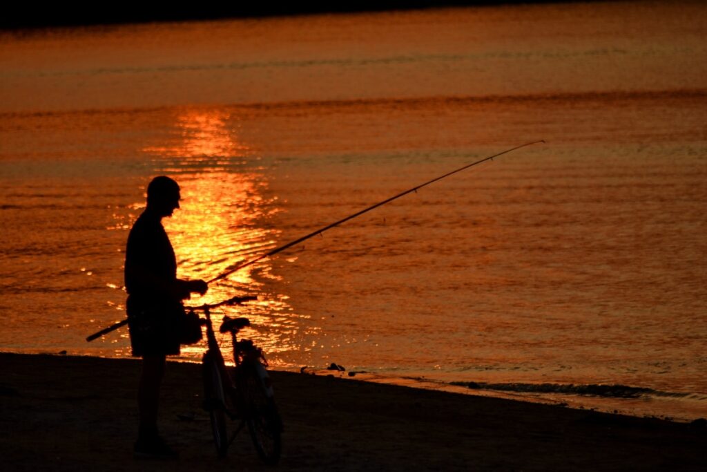 Pescador en la orilla pescando en el crepúsculo